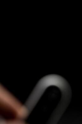 Blurry close-up of hand holding a curved, metallic object by Industrial Designer Simon Busse Studio for ABUS Smart Vest Pro.