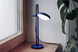 Minimalist blue “Echo” designer lamp by Simon Busse, placed on a wooden windowsill.