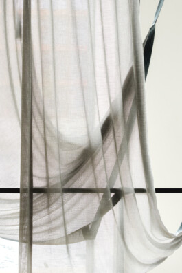 At Simon Busse Studio, sheer white curtains are designed to hang in elegant, soft folds, allowing sunlight to filter softly through the fabric. Behind this layered textile, the subtle and blurred outlines of three hammocks evoke a harmonious industrial aesthetic—combining lightness and structural clarity characteristic of Simon Busse’s industrial design approach.